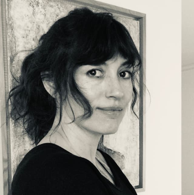 A black and white portrait of a woman with dark, wavy hair and a pensive expression, set against a textured background.